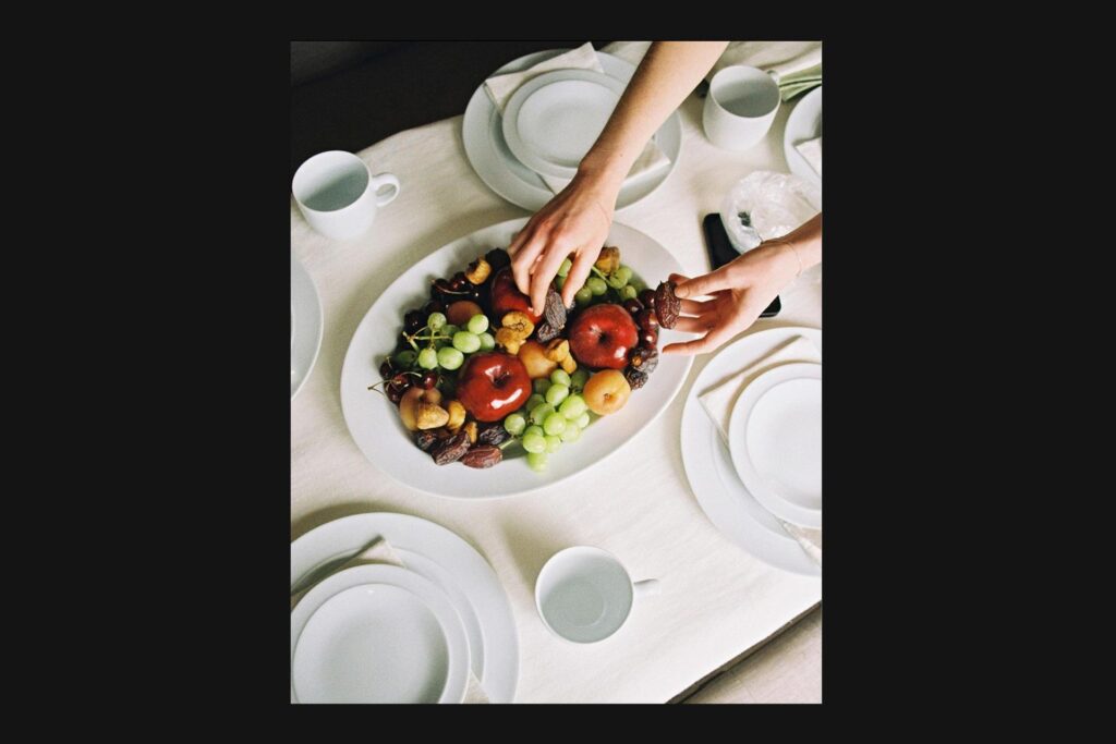Plate of food on table with hand reaching in to grab an item